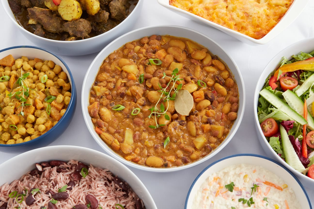 A spread of authentic Jamaican dishes: jerk chicken, curry goat, oxtail, rice and peas, plantain